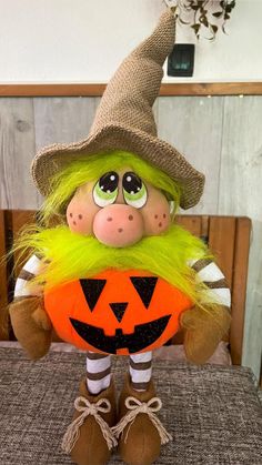 an orange and green trolly doll sitting on top of a table next to a pumpkin