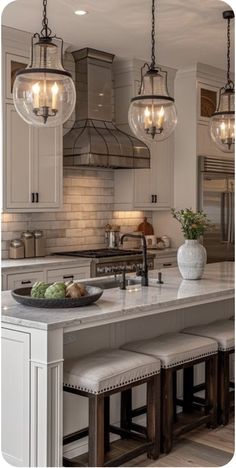 a kitchen island with stools and lights hanging over it