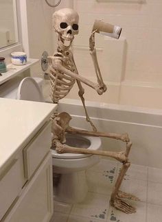 a skeleton sitting on the toilet in a bathroom with its arms and legs spread out