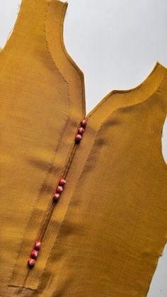 a yellow top with red beads on it