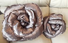 two decorative flower pillows sitting on top of a white couch next to each other,