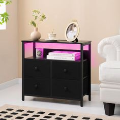 a living room with a white chair and black dresser