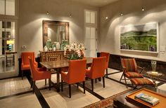 a dining room with orange chairs and a wooden table in the middle of the room