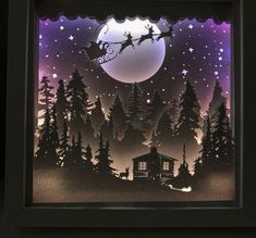 a paper cut christmas scene with santa's sleigh flying over the forest