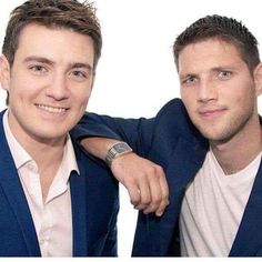 two men in suits posing for the camera with their arms on each other's shoulders