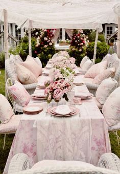 a table set up with pink and white flowers in vases, plates and napkins