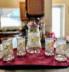 a pitcher and four glasses on a table