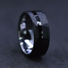 a black diamond ring sitting on top of a gray surface with an inscription in the middle