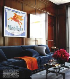 a blue couch sitting in front of a window next to a table with flowers on it