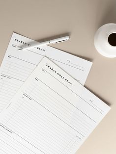 two sheets of paper sitting on top of a desk next to a cup of coffee