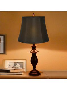 a lamp that is sitting on top of a table next to a framed photo and some books