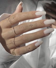 a woman's hand with white manies and tattoos on her fingers is shown