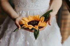 a bride holding a sunflower in her hands