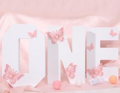 the letters one and two are decorated with pink butterflies, balls, and cotton swabs