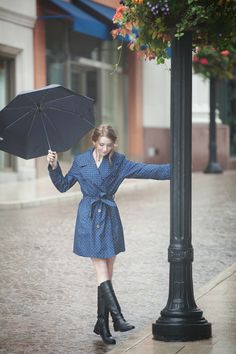 a woman holding an umbrella while standing next to a lamp post