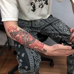 a person with a dragon tattoo on their arm sitting in front of a computer desk