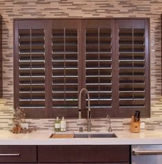 a kitchen with wooden shutters and marble counter tops