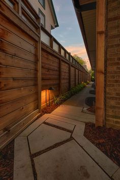 a wooden fence next to a building with a light on it's side and the door open