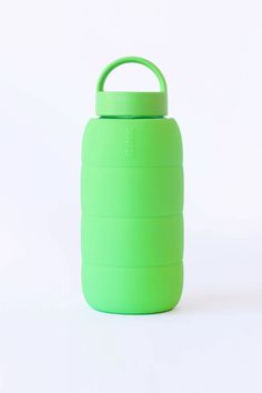 a green water bottle sitting on top of a white table