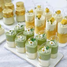 there are many small desserts on the table with white and yellow flowers in them