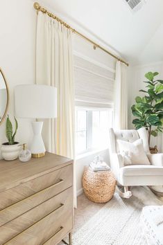 a living room with white furniture and a large round mirror on the wall above it