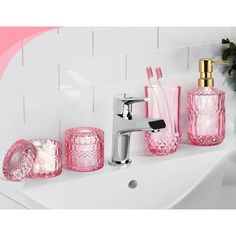 pink bathroom accessories sitting on top of a white sink