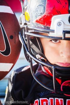 a young boy wearing a football helmet and holding a football