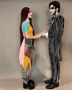 two people dressed in costumes standing next to each other and one is holding the hand of another person