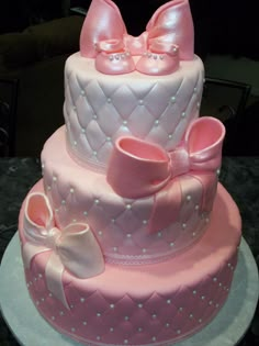 a three tiered cake decorated with pink bows and diaper on the bottom layer