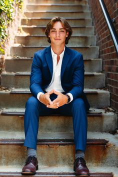 a man in a suit sitting on the steps with his hands clasped to his chest