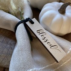 a white pumpkin sitting on top of a wooden table next to a napkin with a name tag