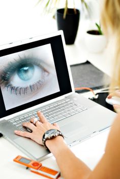 a woman using a laptop computer with an eye on the screen