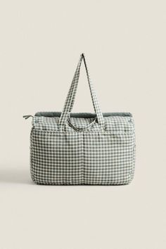 a green and white gingham bag sitting on top of a gray floor next to a wall