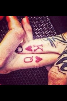 two people with tattoos on their hands holding each other's fingers and the word love is