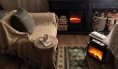 a living room with a fire place in the corner and blankets on the floor next to it