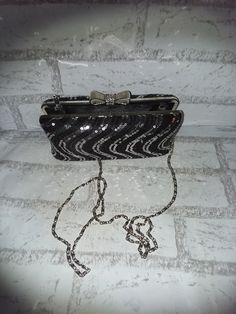 This glitzy little clutch is perfect for the holidays. It is about 7 inches long and 4 inches tall. Lift the top bow and it opens wide enough to fit your hand. All the rhinestones are present and accounted for on the bow clasp. The body of this purse is sequins, sequins, sequins.  The chain handle is 24 inches from the purse so about 48 total. Long enough to cross over most bodies. When not in use it tucks completely inside the clutch. I cannot find a maker tag on this purse. A great gift or a little glam for yourself. Party Clutch Bags With Bow Detail, Party Clutch Bags With Bow, Glamorous Glitter Evening Bag As Gift, Glamorous Glitter Evening Bag For Gifts, Glamorous Silver Glitter Clutch, Silver Glitter Clutch For Evening, Glamorous Evening Clutch With Glitter, Elegant Glitter Evening Bag As Gift, Glamorous Glitter Clutch For Evening