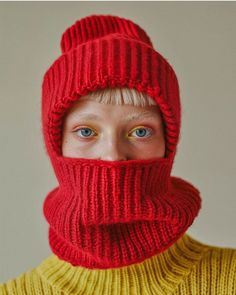 a person wearing a red knitted hat and scarf over their face with the hood pulled up