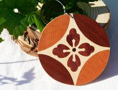 a wooden keychain with a flower design on it sitting next to a potted plant