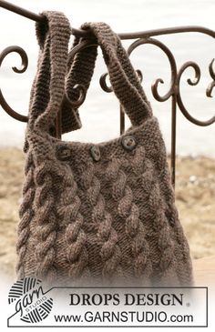 a handbag is hanging on a metal rail by the beach with waves in it