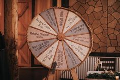 a wooden wheel with words written on it sitting in front of a table and chairs