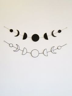 the moon and phases are hanging on a string in front of a white wall with black circles