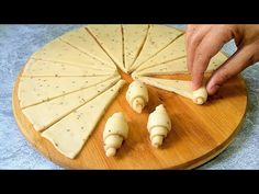 a person is cutting cheese on a wooden platter with four pieces cut out to look like shells