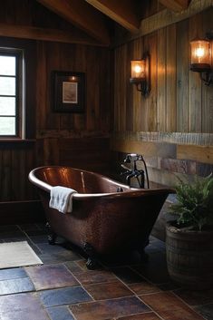 an old fashioned bathtub in the corner of a rustic bathroom with wood paneling