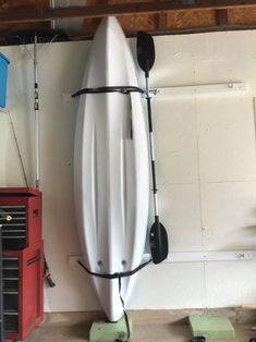 a white surfboard sitting on top of a wooden floor next to a red toolbox