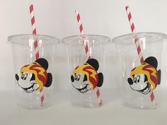 three mickey mouse cups with red and white striped straws on the top one has a cartoon character's head