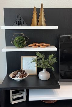 a black and white entertainment center with two shelves on each side, decorated with pineconi