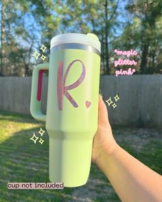 someone holding up a cup with the letter r painted on it