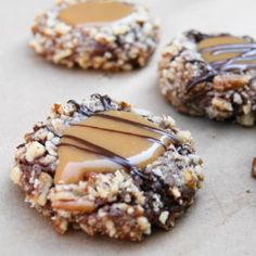 cookies with peanut butter and chocolate drizzled on top, sitting on a baking sheet