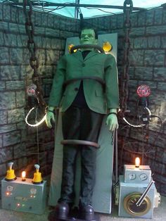 a statue of a man in a green suit holding a cane and standing next to an electrical device