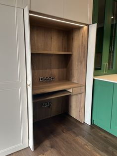 an empty room with green cabinets and white cupboards on the wall, next to a wooden floor